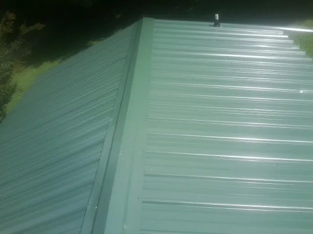 New green metal panels meeting at the ridge of a roof — Flat Roof Repair work by our crew in Smelterville