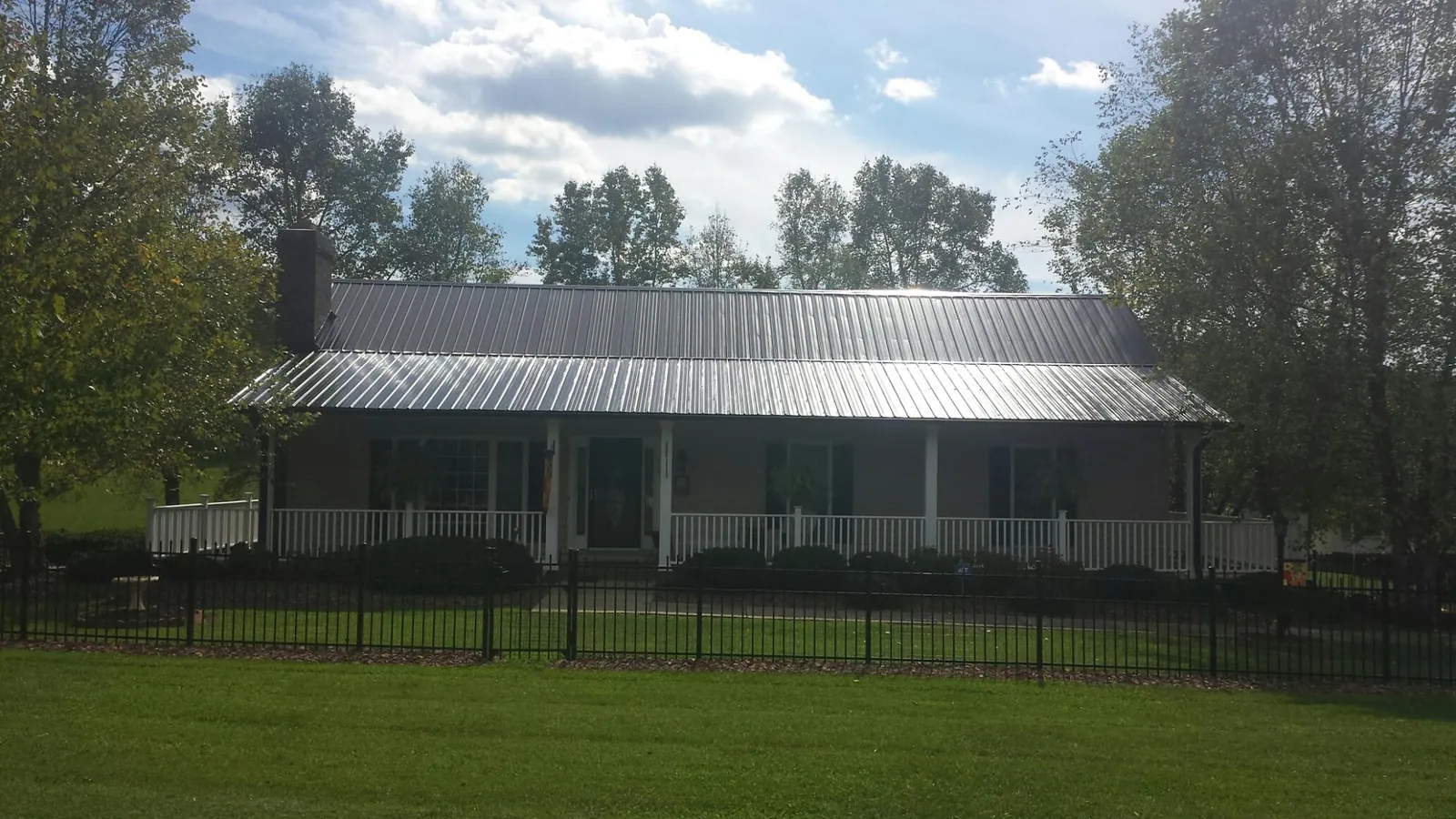 Gray metal roof on a brick ranch with a full width front porch — Gutter Guard Installation work by our crew in Smelterville