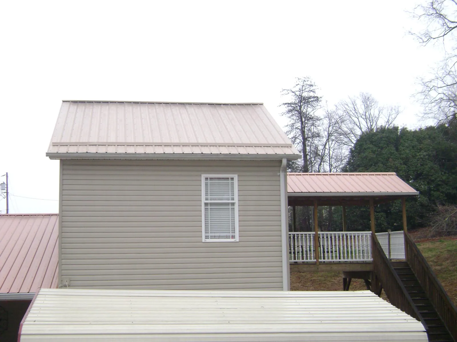 Tan metal roofs on a two story addition and attached porch, from a Roof Replacement job in Smelterville