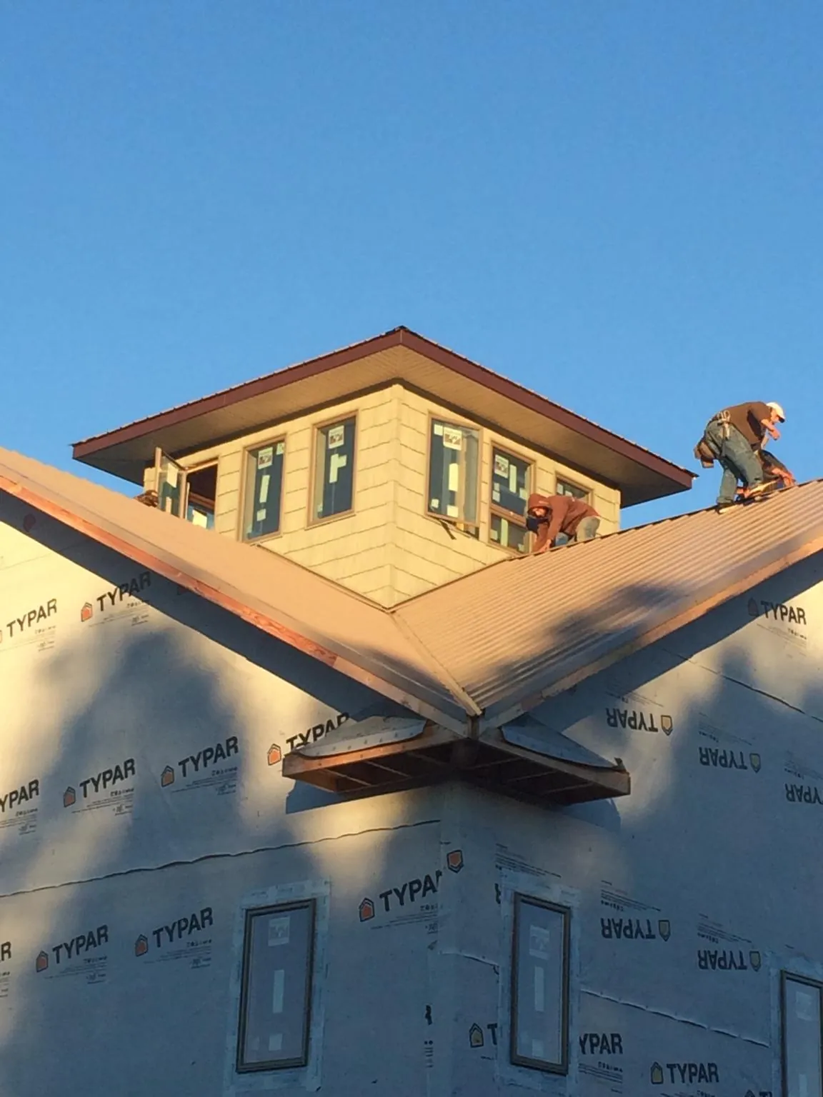 Roofers working around a rooftop cupola on a new metal roof at sunset — Roof Waterproofing in Smelterville by Roofing Brothers